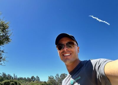 Dr. Joshua B. Fisher (Linacre JRF 2009), Science Lead for Hydrosat, with the Hydrosat satellite being launched on a SpaceX rocket in the background.